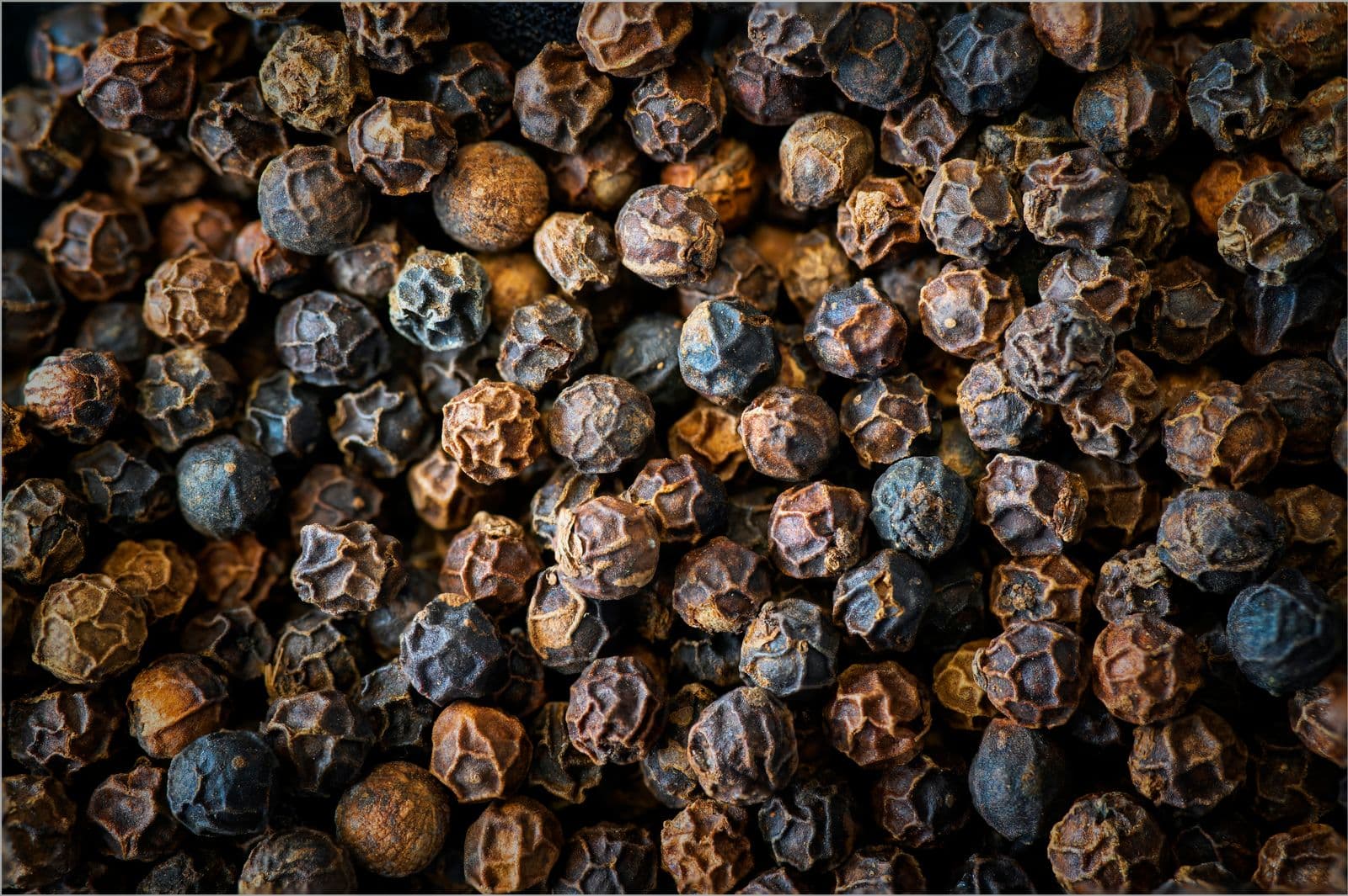 Dried black peppercorns, showing the wrinkled surface of each berry